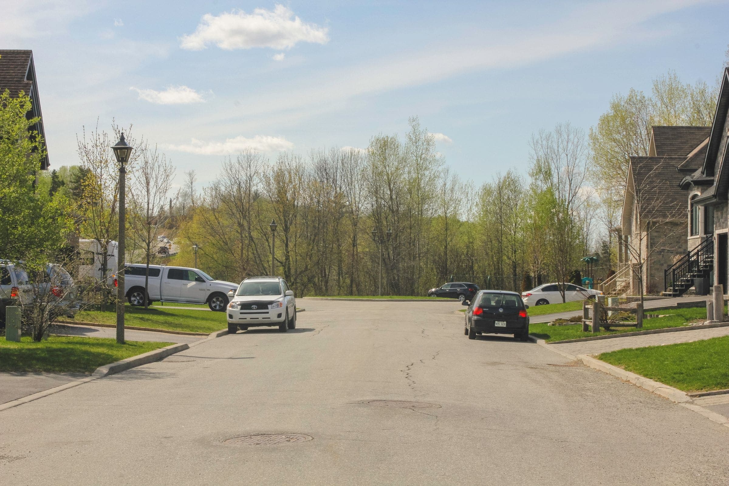 Quiet suburban street with pickup trucks and houses in early spring