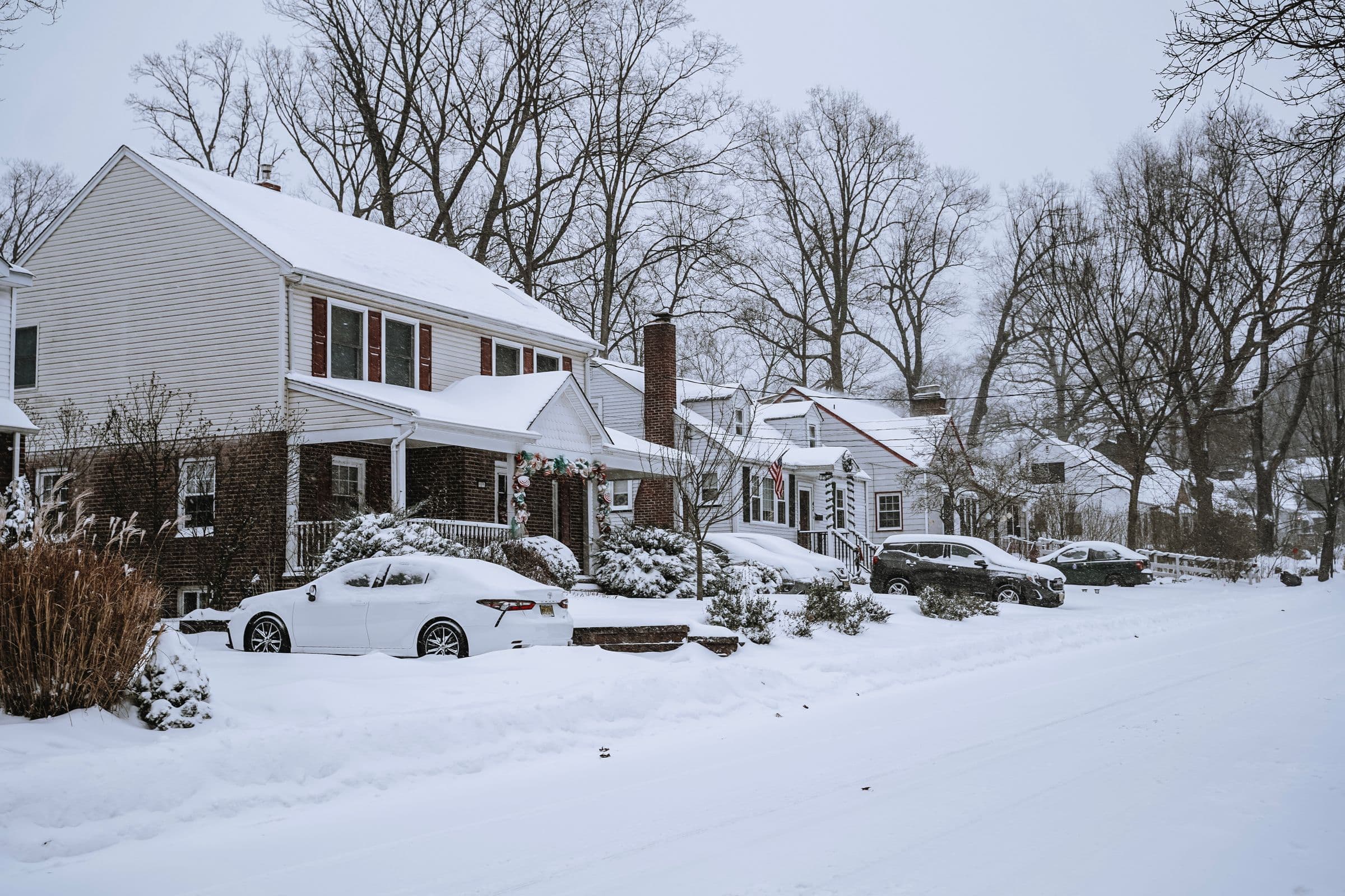 Snowy residential street with older two-storey houses and bare trees