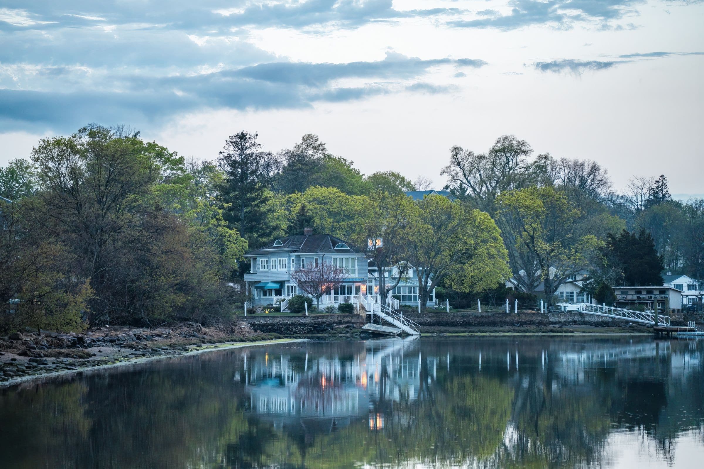 Lakeside homes among trees reflected in calm water