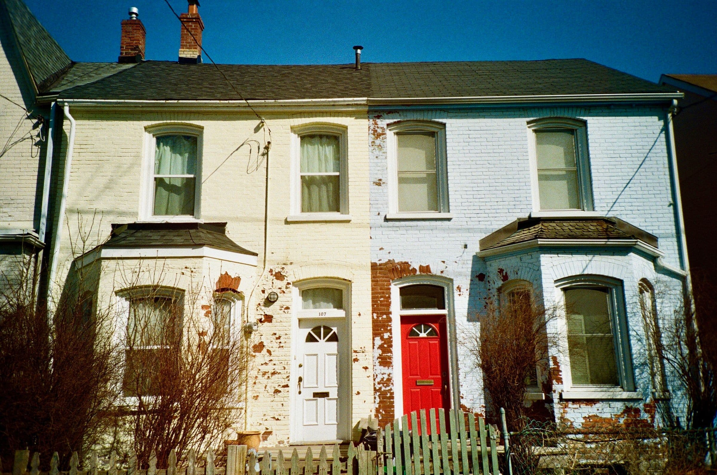 Pair of old brick semi-detached houses with bay windows and a red door