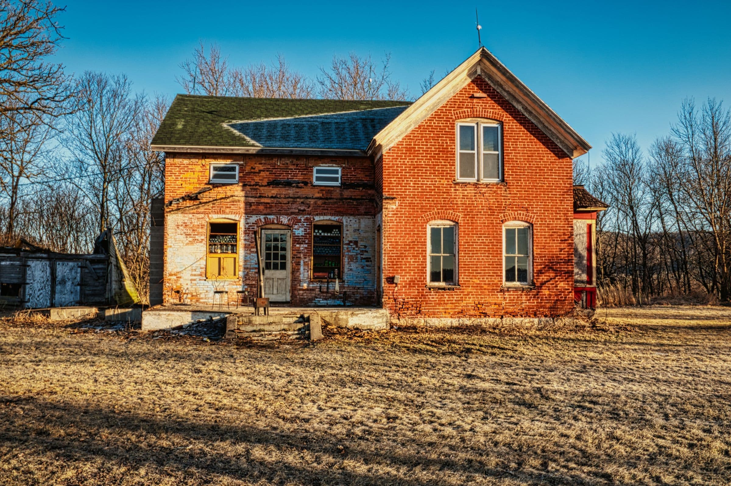 Old red brick farmhouse beside a ploughed field